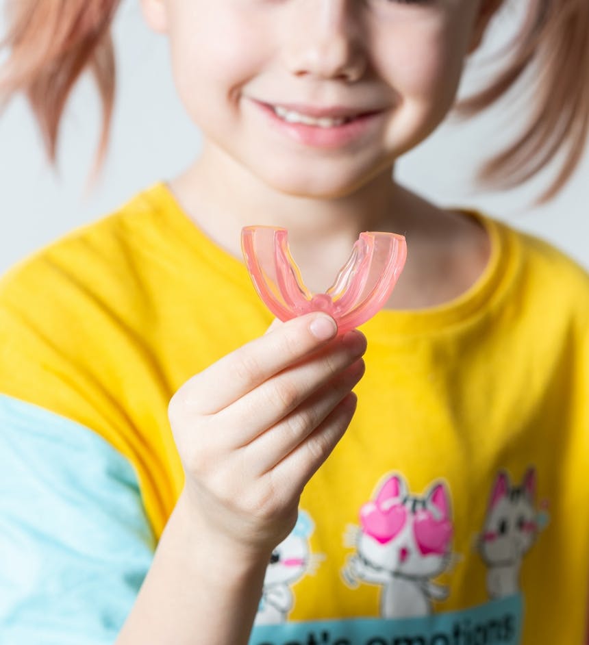 cute-little-girl-with-blond-hair-is-holding-pink-dental-myofunctional-trainer